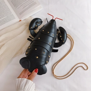 Close-up of black lobster crossbody bag with gold rivets and chain strap detail