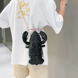 Detail of creative black lobster crossbody bag with gold studs and a gold chain strap