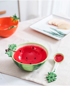 Close-up of watermelon-shaped ceramic bowl and spoon set with vibrant fruit patterns