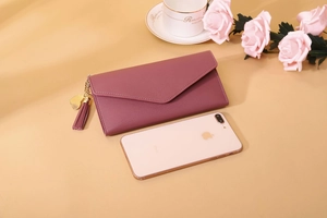 Detail view of pink long envelope wallet featuring a tassel and golden heart charm