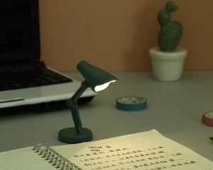 Mini lampe LED verte pliable à lumière chaude avec bras flexible sur bureau d'étude