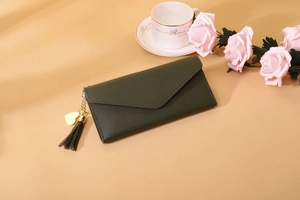 Detail einer olivgrünen Umschlag-Brieftasche mit Narbenleder und Herzanhänger
