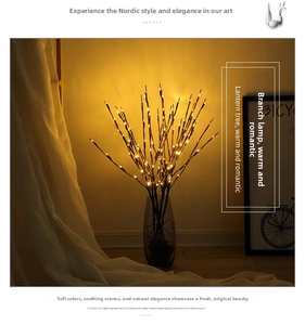 Detail of warm LED willow branch lights in a clear glass vase for cozy home decoration
