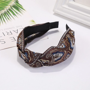 Detailed close-up of dark brown fabric headband with intricate ethnic gold and blue embroidery