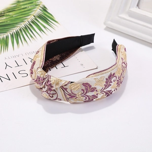 Close-up of floral embroidery on wide knotted headband with elegant purple petals
