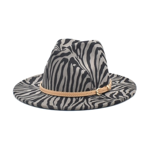 Close-up of zebra pattern fedora hat featuring a brown leather band and gold buckle