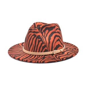 Detail of orange zebra print fedora featuring a khaki faux leather band and metal buckle
