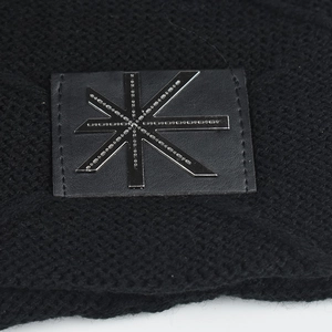 Detail of black knit beanie featuring a faux leather patch with a silver star metallic logo