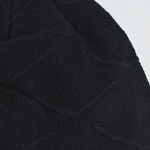 Detailed macro shot of the black geometric knit texture and soft lining of this winter hat