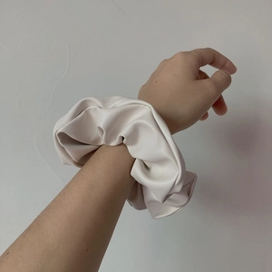 Close-up of a large white faux leather scrunchie worn on hair with a soft texture