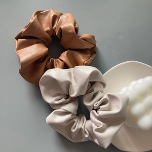 Close-up of brown and cream faux leather scrunchies with soft glossy texture