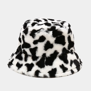 Close-up of fluffy black and white cow print bucket hat with soft plush faux fur texture