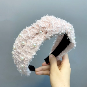 Detail of pink feather yarn headband with pearl accents and knotted wide tweed texture
