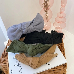 Bow velvet headbands in grey black green and khaki displayed on a woven basket