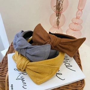 Three velvet bow headbands in brown, grey, and yellow displayed on an open magazine