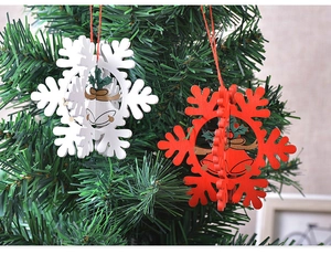 Close-up of red and white 3D wooden snowflake and bell ornaments on a green Christmas tree