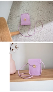 Close-up of purple crocodile pattern mini bag with gold lock next to a vase with dried flowers