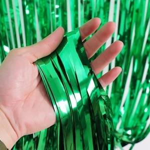 Close-up of green metallic laser tinsel curtain texture held by hand for party decor