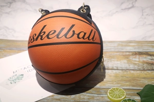 Detail of creative orange basketball shaped bag with gold hardware on wooden surface