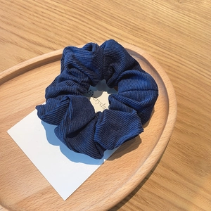 Detailed texture of dark blue corduroy scrunchie on a decorative white card