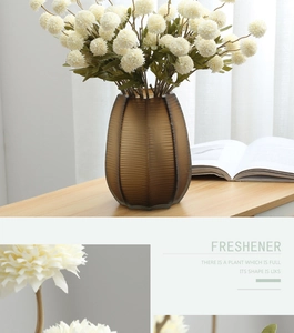 Detailed view of white pompom chrysanthemums in a brown ribbed glass vase on a wooden table