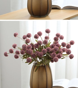 Detailed close-up of purple faux dandelion balls in a brown ribbed glass vase decor