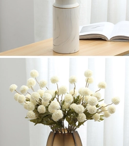 Detail of cream artificial dandelion flowers in marble and amber glass vases for decor