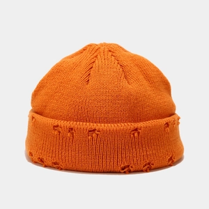 Detailed close-up of orange knitted beanie showing the distressed rip design and thick texture