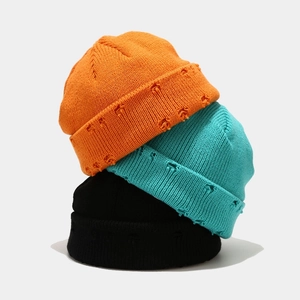 Close-up of ribbed knit beanies in multiple colors featuring distressed ripped edge details