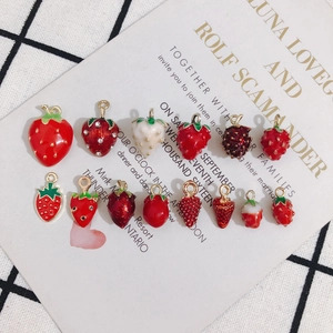 Flat lay of colorful enamel strawberry charms for DIY jewelry making on grid background