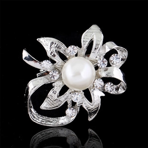 Detailed view of silver flower brooch with hollow rhinestone petals and center pearl