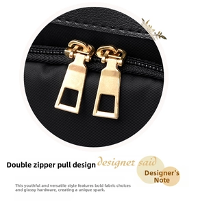 Detail view of the golden metal dual-slider zipper on a black oxford fabric backpack