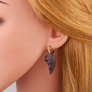 Detail view of leaf drop earring with purple rhinestones and golden hoop on a model