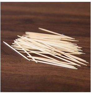 Detailed close-up of sharp natural bamboo toothpicks scattered on a dark wooden table