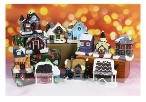 Detailed view of various miniature resin Christmas houses with snow accents and warm glowing lights