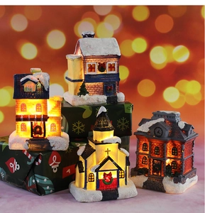 Close-up of four light-up Christmas resin village houses with warm LED glow and snow detail