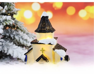 Macro shot of glowing Christmas church miniature with snow-capped roof and warm LED light
