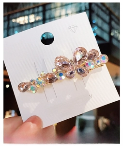 Macro detail of butterfly hair clip with pink pear-cut crystals on gold metal base