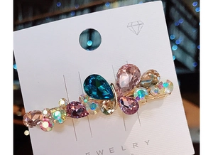 Macro detail of butterfly hair clip with colorful K9 crystals on a display card