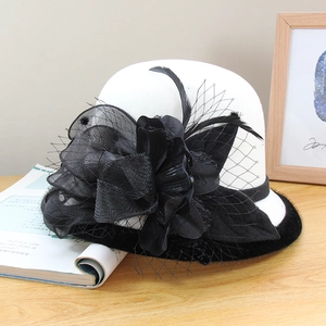Detail of white wool felt hat with black mesh veil, feather and floral accents