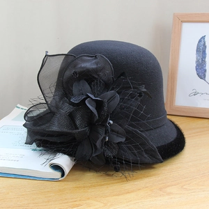 Detail of vintage black wool hat with mesh veil, silk flower, and feather accents