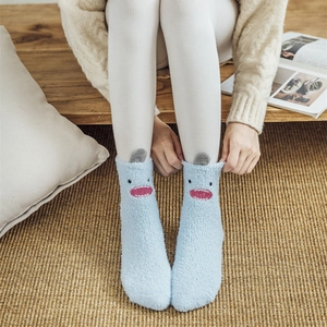 Cozy light blue coral fleece monster socks with cute cartoon design on wooden floor