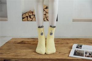 Detail of yellow cartoon monster socks in soft coral fleece with 3D ears and eyes