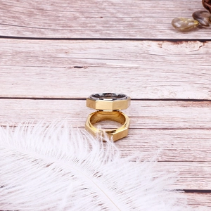 Détail d'une bague géométrique hexagonale plaquée or 18K sur fond de bois rustique