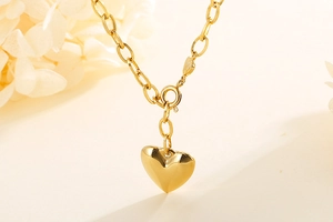Macro shot of a polished gold heart pendant with a delicate link chain on soft background