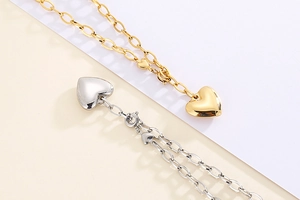 Detailed shot of polished gold and silver heart pendants on chunky metal chains
