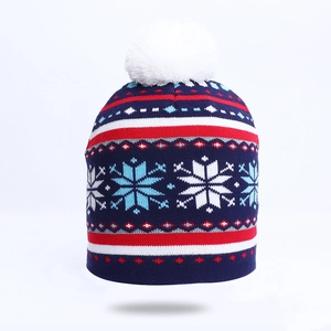 Close-up of knit winter beanie featuring snowflake patterns and a large white pompom