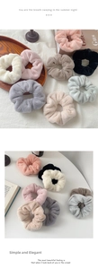 Detailed texture of plush scrunchies in pastel colors on a wooden tray and white desk