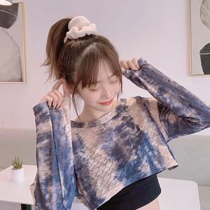 Fuzzy beige plush scrunchie shown on a woman styling a tie-dye knit crop top in cozy interior