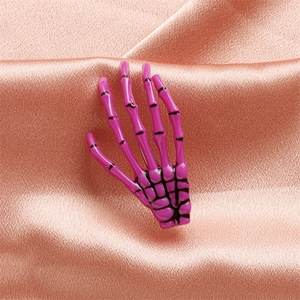 Detail of purple skull claw hair clip on silk background with glossy finish texture